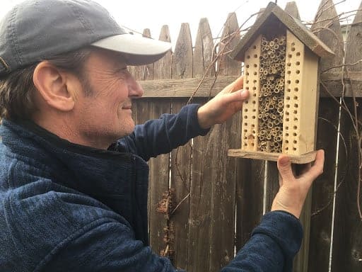 Hanging the finished mason bee hotel on a fence post.