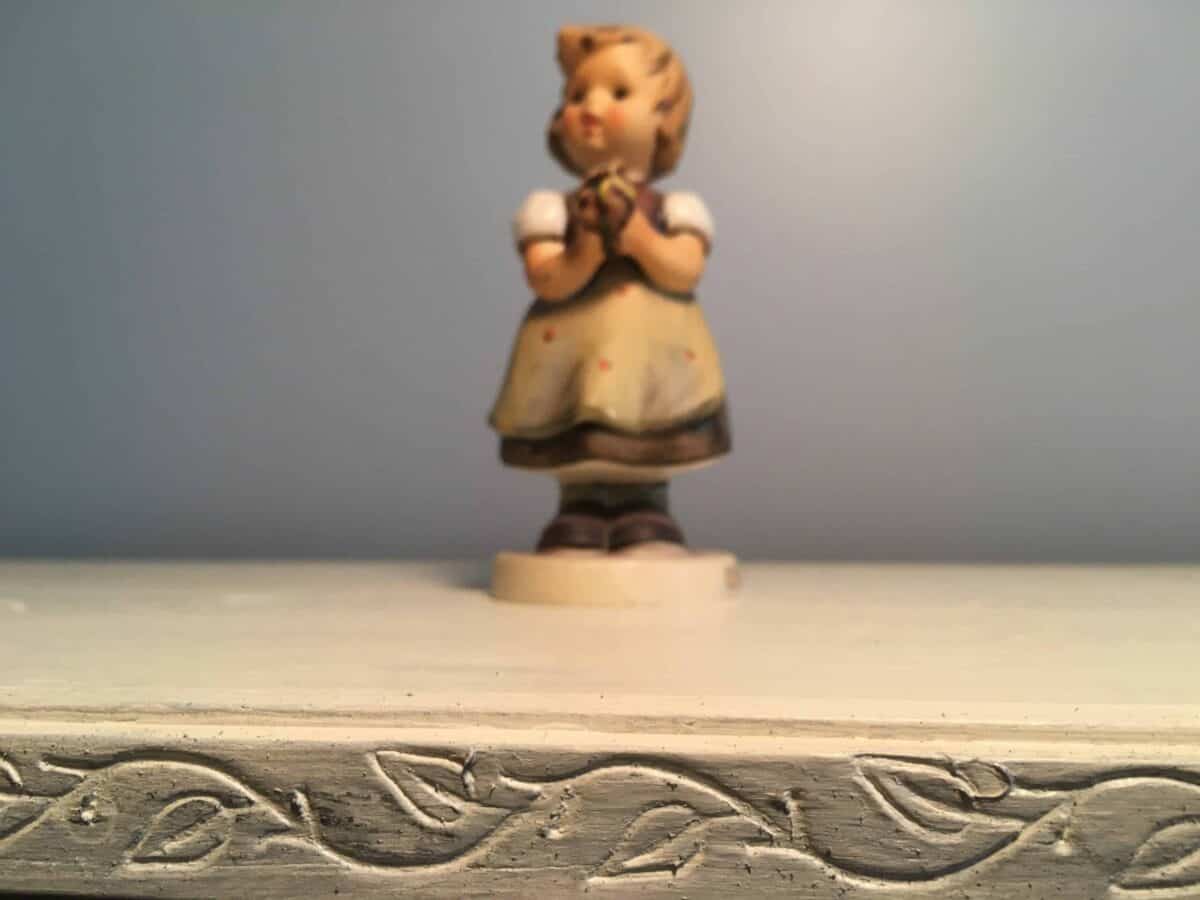 Close up of trim and top of bookcase, with one my grandmother's Hummel figurines on top.