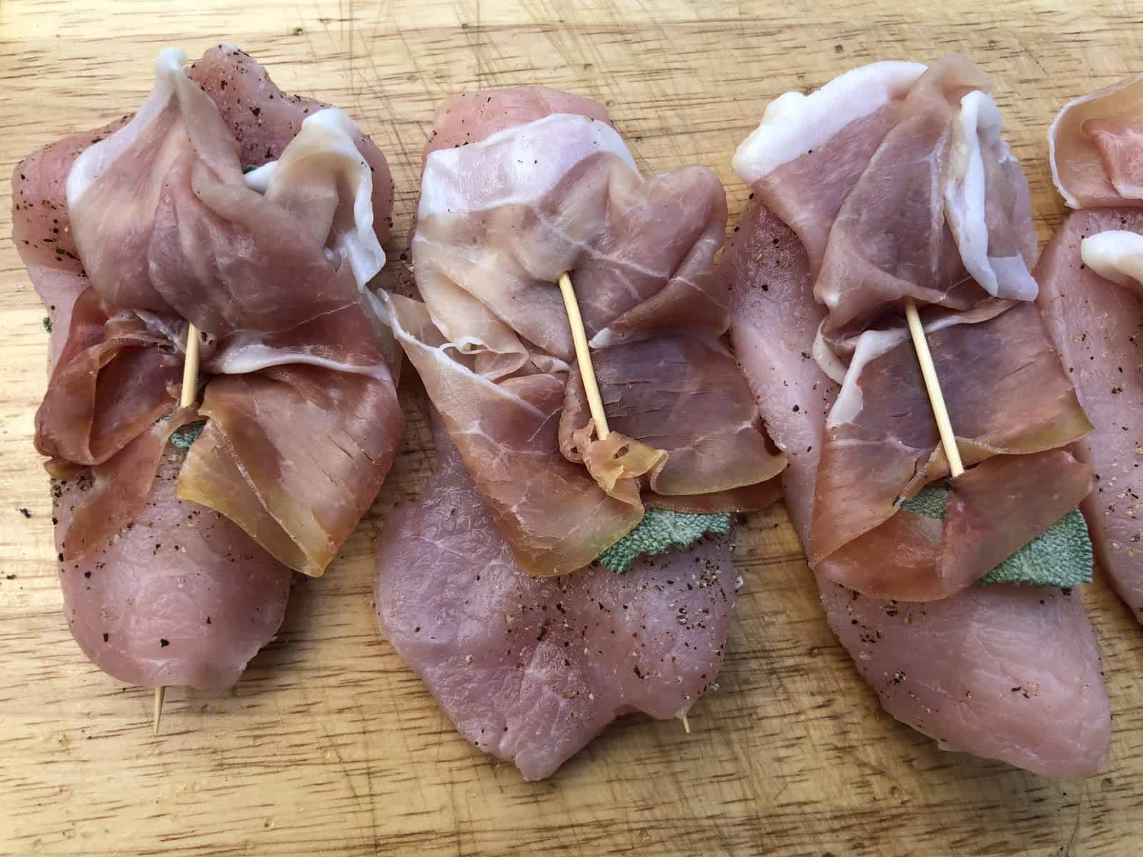 Prosciutto and sage on cutlet with a toothpick.