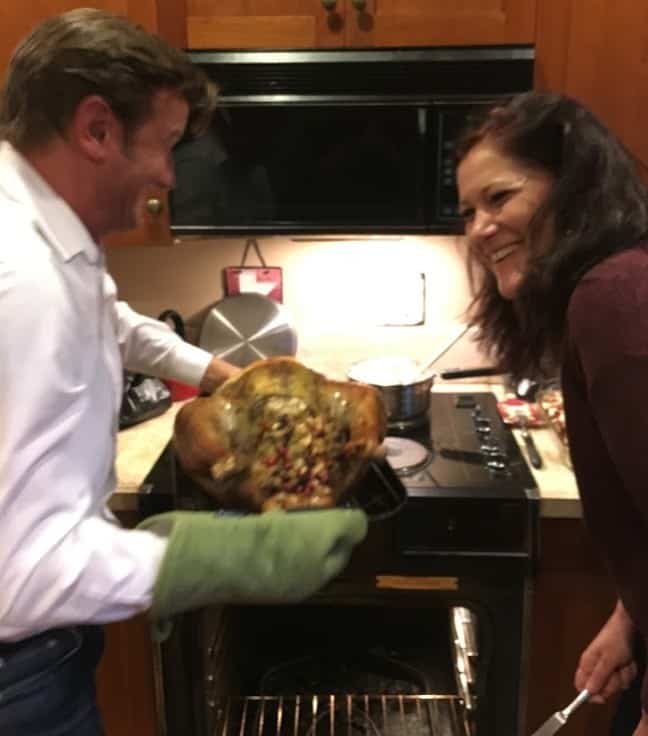 Erich and Viana laughing while taking the turkey out of the oven.