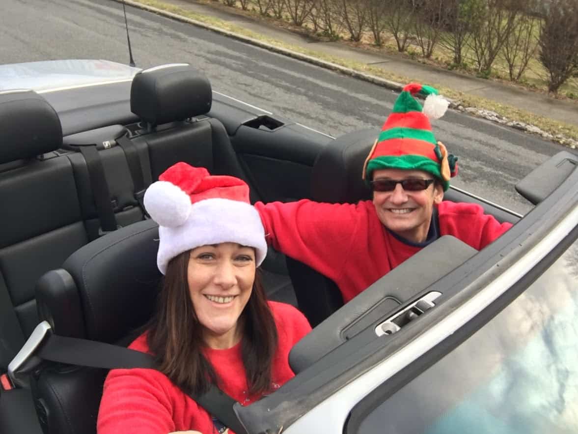 Viana and Erich dressed up in Christmas hats, driving in convertible.