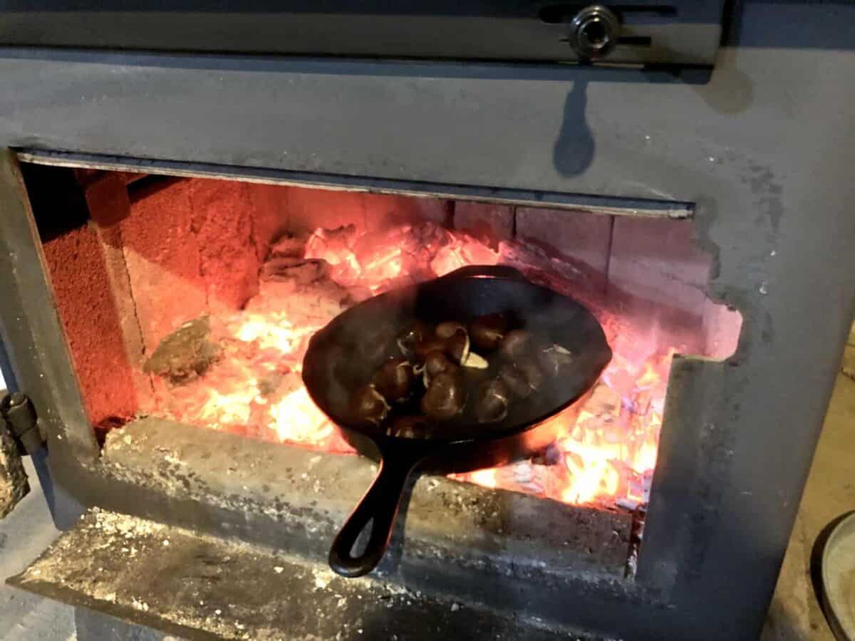 Chestnuts roasting on an open fire in a wood stove.