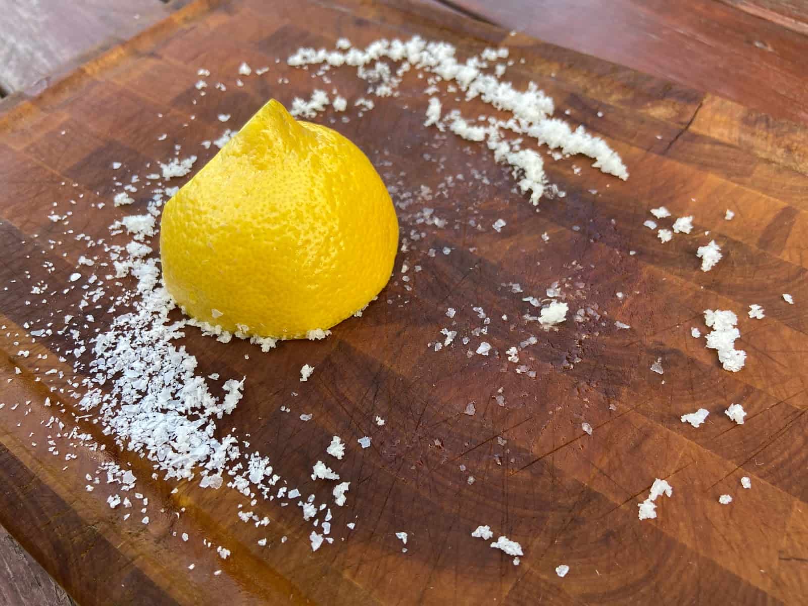 Cutting board with sliced lemon and salt on top.
