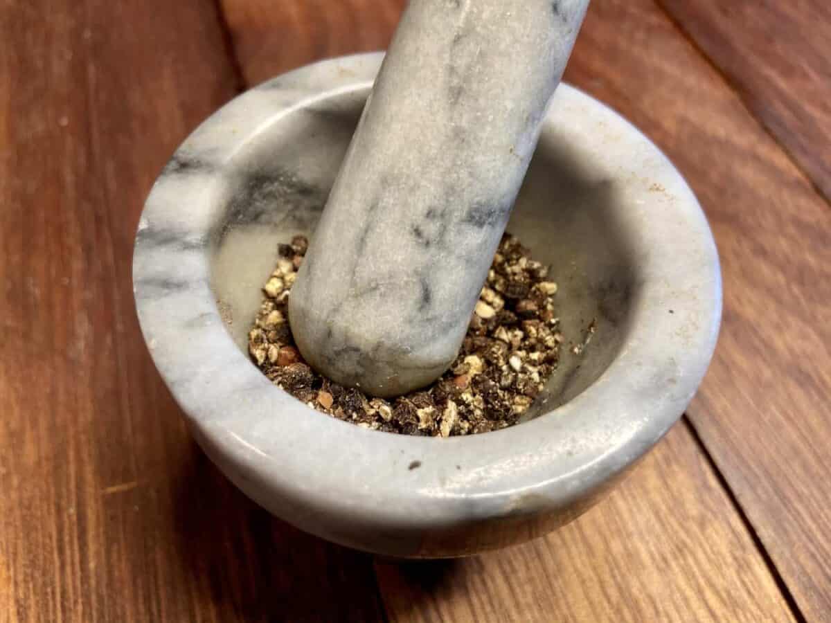 Grinding peppercorns in a small marble mortar and pestle.