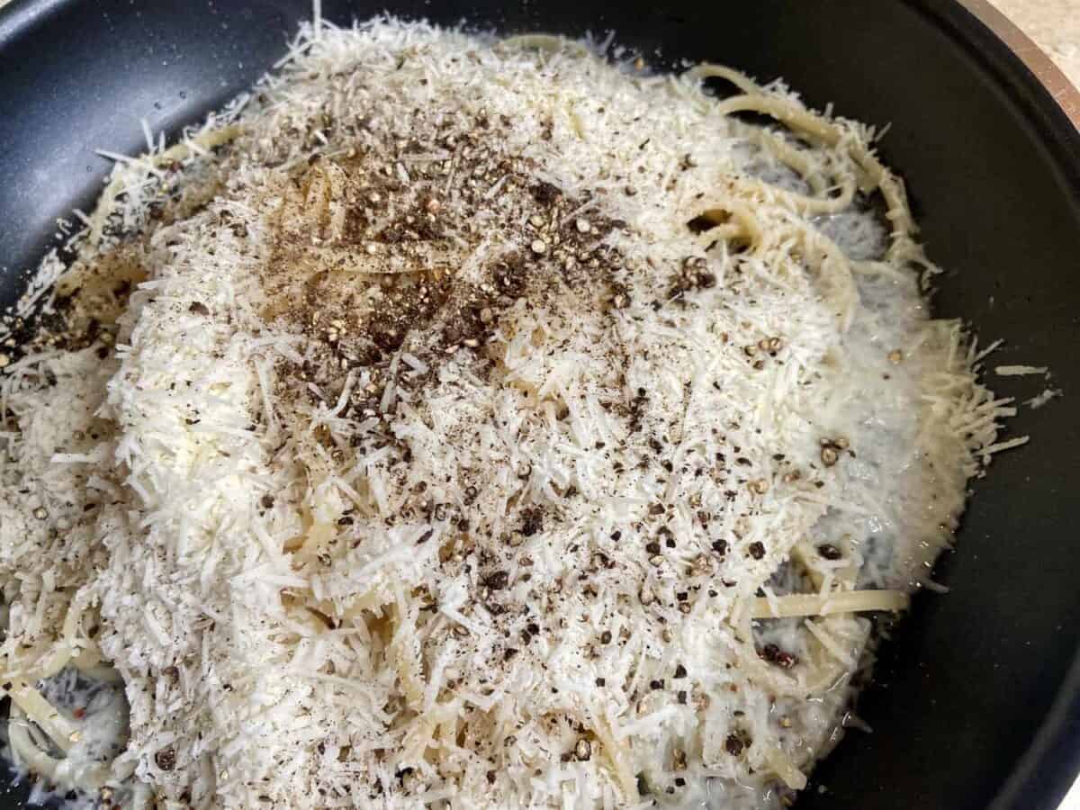 Mixing pasta with cheese and pepper in a pan.