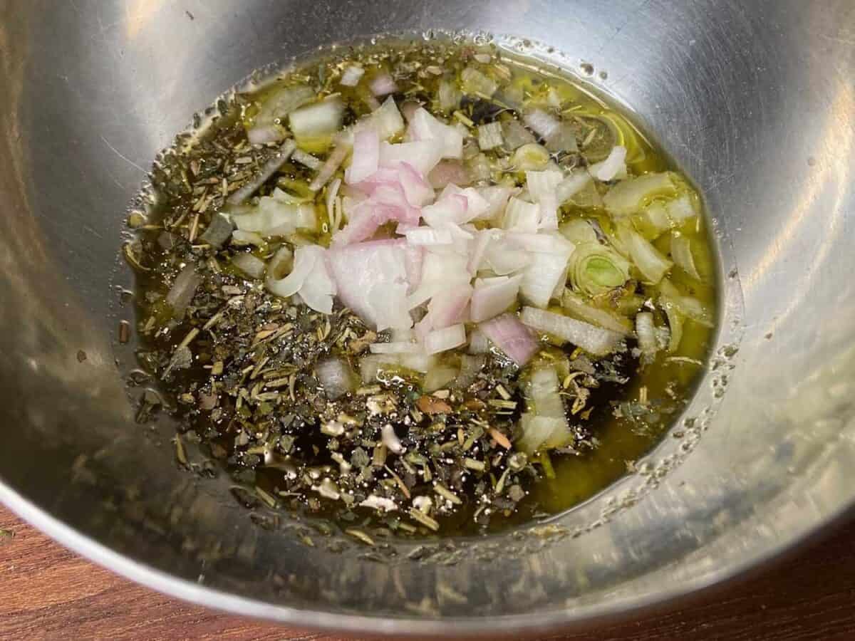 Oil, vinegar, and seasonings in a bowl.