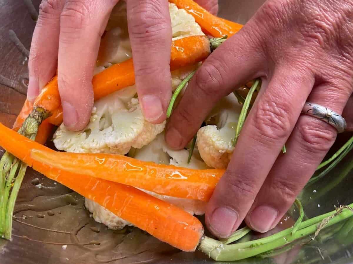 Spreading olive oil over vegetables.