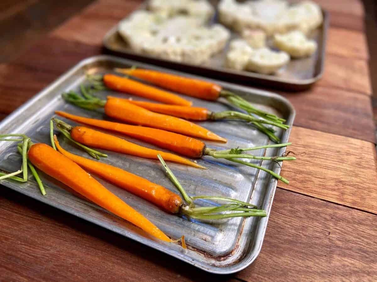 Carrots and cauliflower on roasting pans.