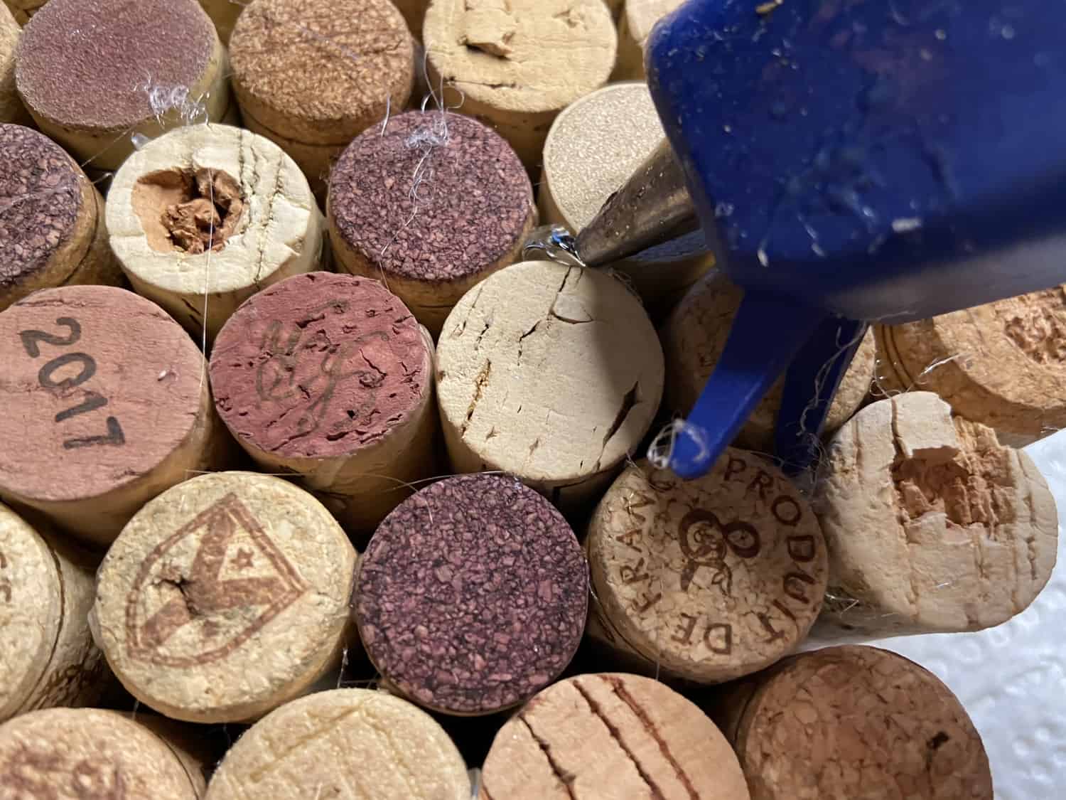 Using hot glue gun to place glue between the corks.