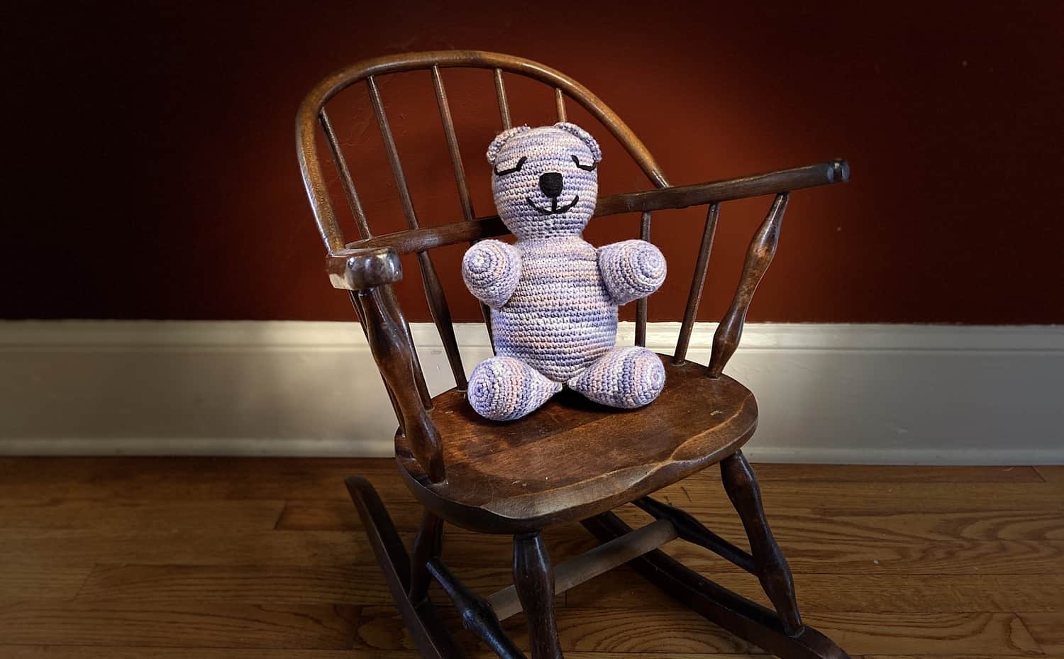 Bear sitting in a child's rocking chair.