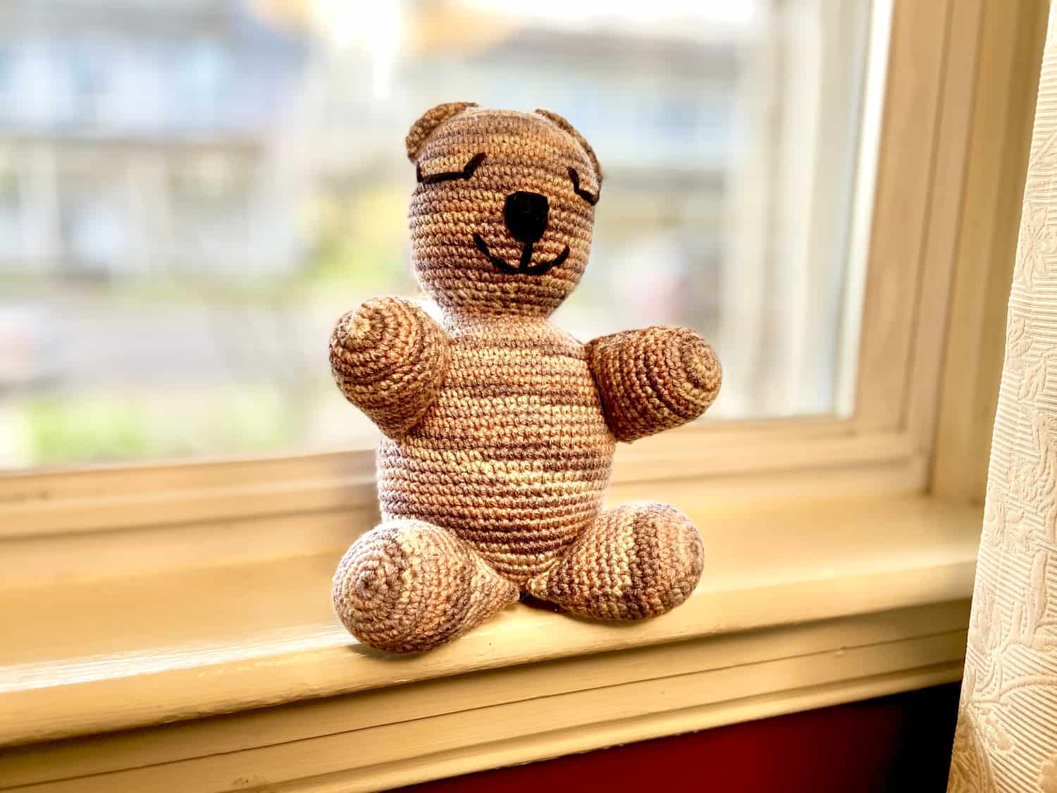 Bear sitting on a window sill.