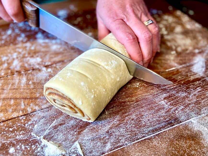 Slicing the rolled up dough into individual roll sizes.