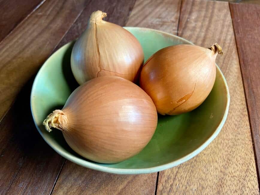 Three sweet vidalia onions in a bowl.