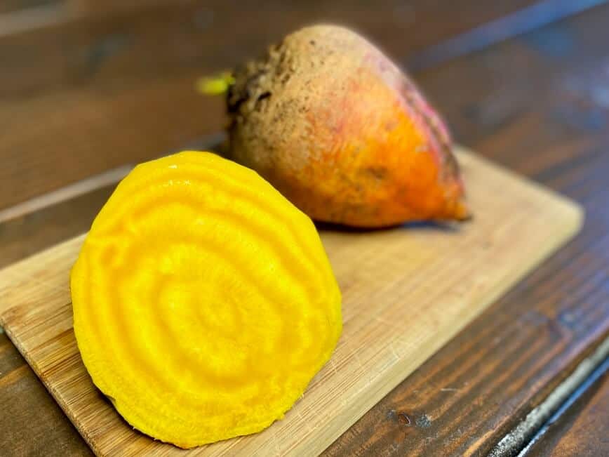 Golden beet sliced in half on a wood cutting board.