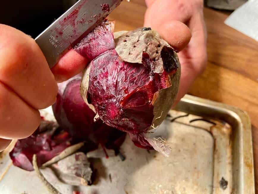 Peeling a baked beet with a knife.