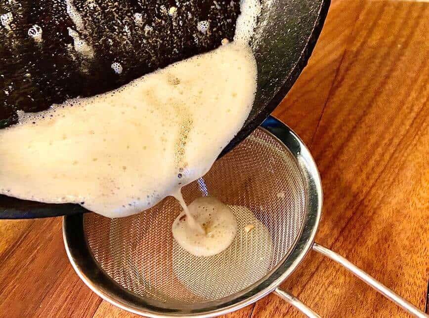Separating garlic from butter through a fine mesh sieve.