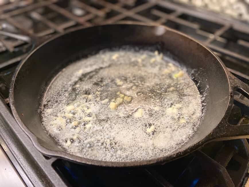 Sauteing garlic in butter in cast iron pan.