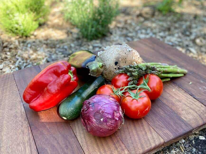 Fresh garden vegetables on wood cutting board.