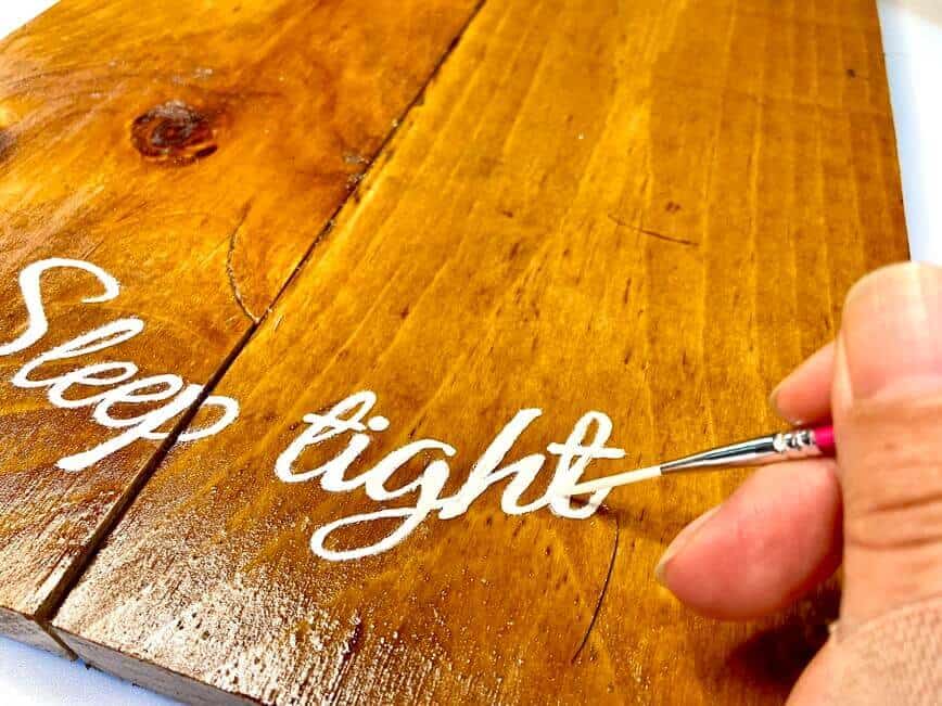 Painting white letters onto the wood.