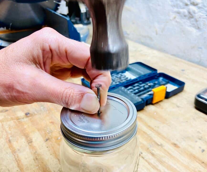 Hammering a nail through the center of the lid.