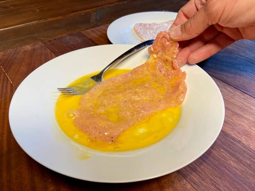Dipping the cutlet in whisked egg.