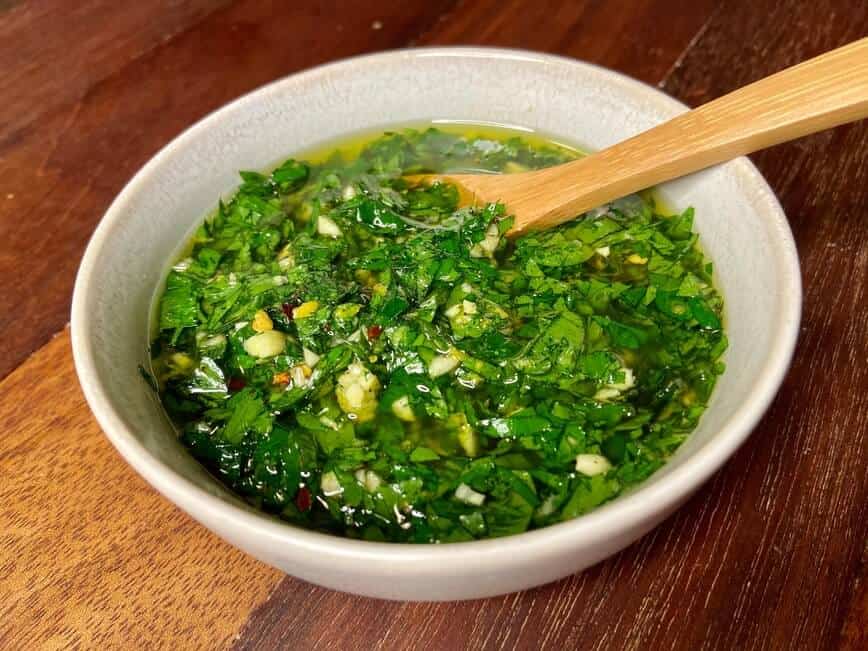 Gremolata mixed in a bowl with a small wooden spoon.