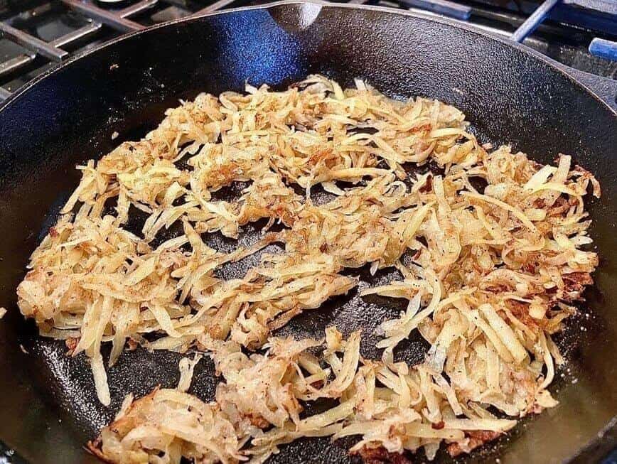 Cooking loose, shredded hash browns in cast iron pan.