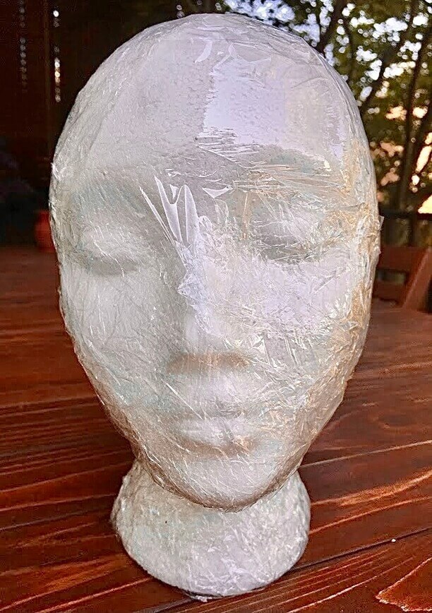Covering the head form in plastic wrap.