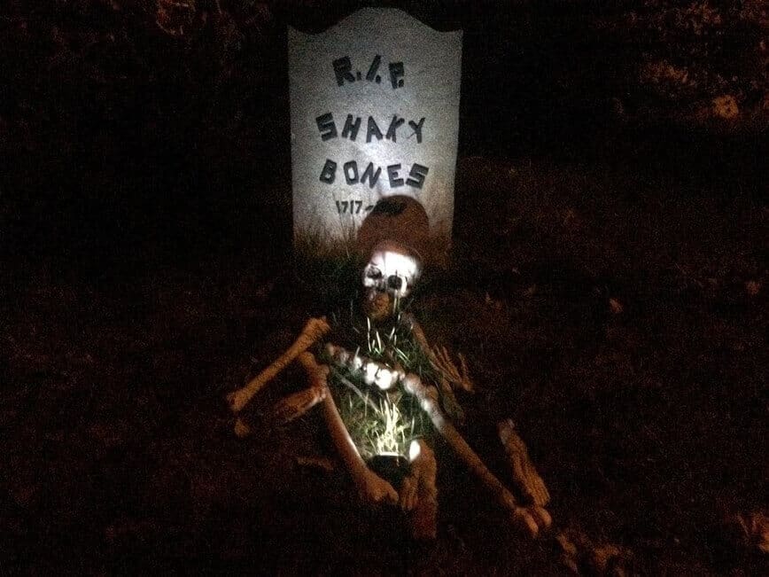 RIP Shaky Bones tombstone, with skeleton on ground.