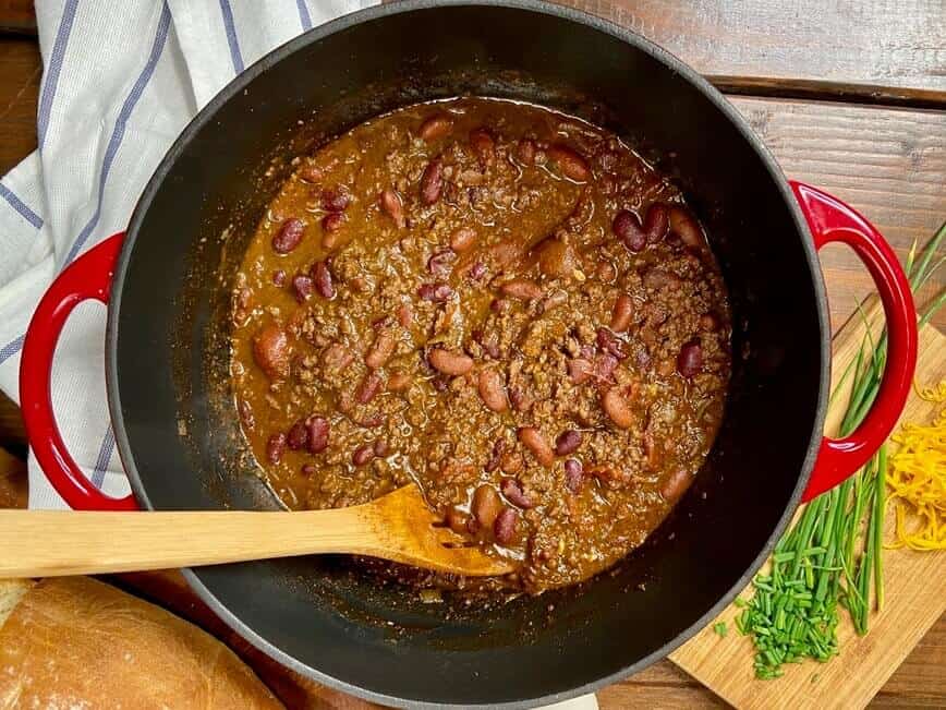 Chili in Dutch oven with a wooden spoon.