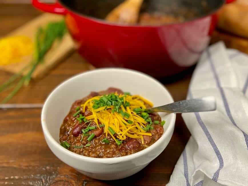Served in a bowl with shredded cheddar cheese and chives on top.
