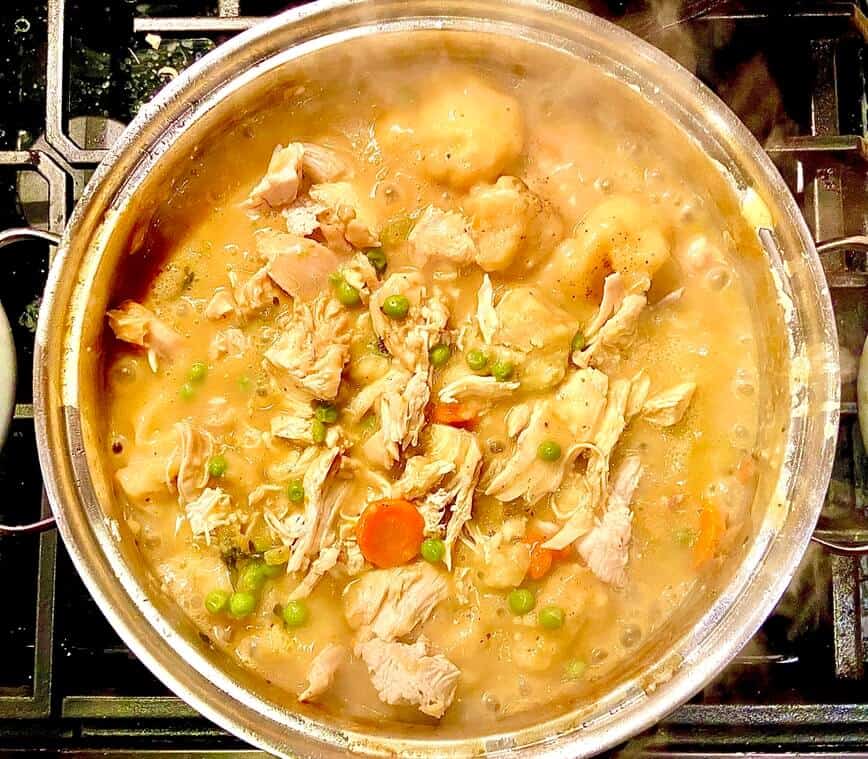 Chicken, dumplings, sauce, and vegetables in pot.
