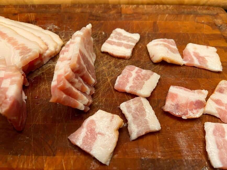 Cut bacon pieces on a wood cutting board.