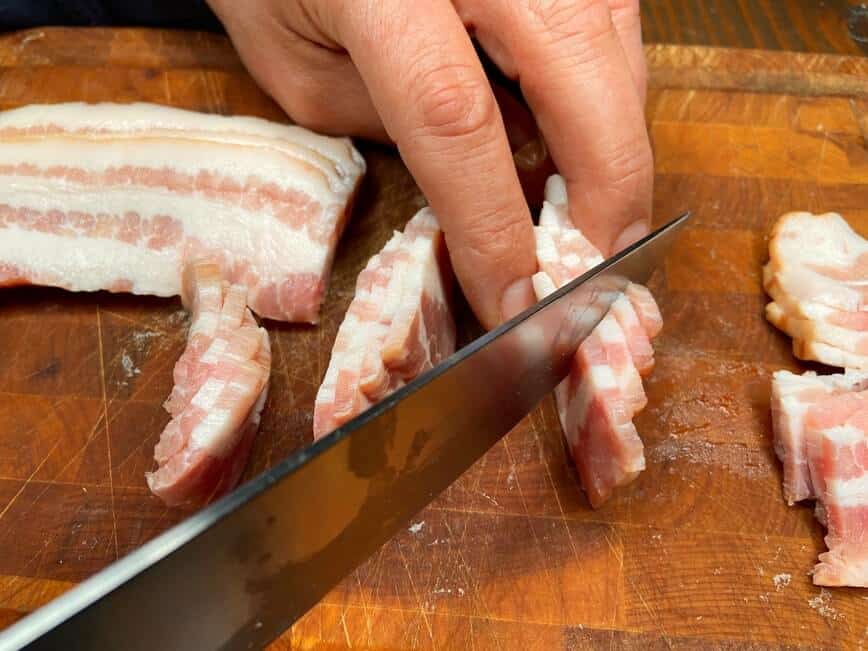 Slicing bacon diagonally.