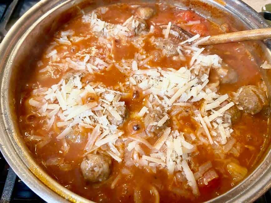 Adding meatballs and cheese to the pot.