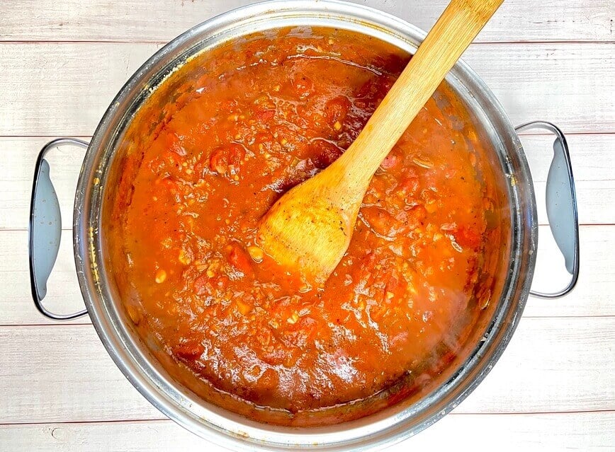 Stirring the sauce in a pot with a wooden spoon.