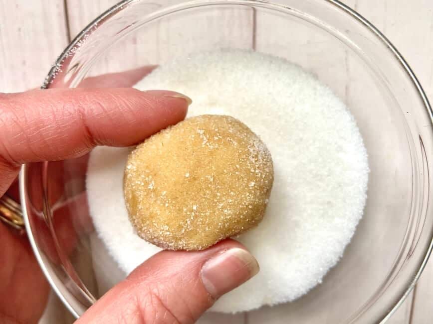 Rolling dough into balls and then rolling them in sugar.