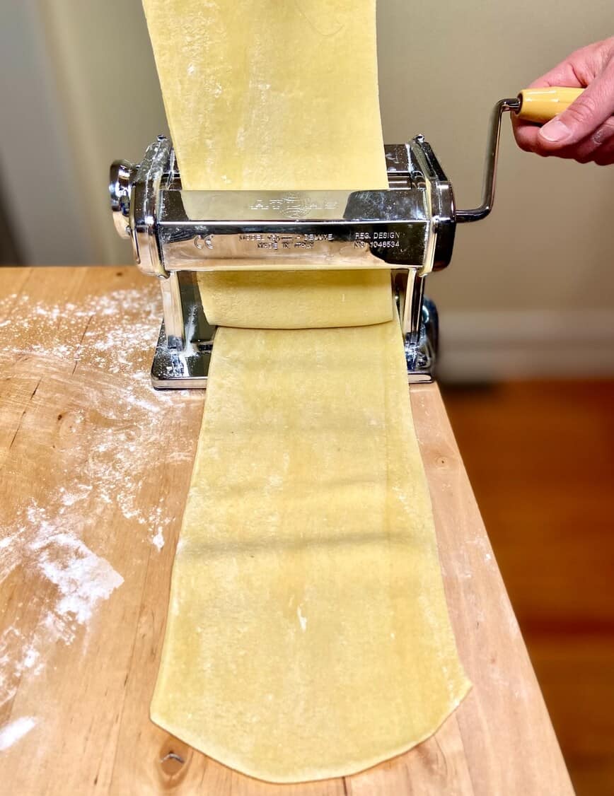 Rolling pasta through pasta machine.
