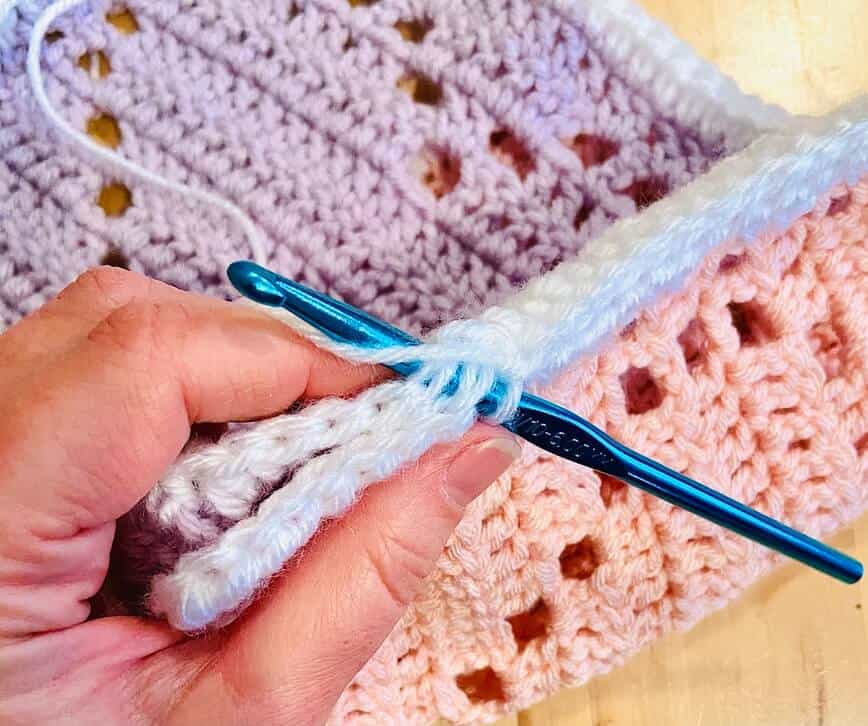 Crochet hook through sides of squares, stitching them together.