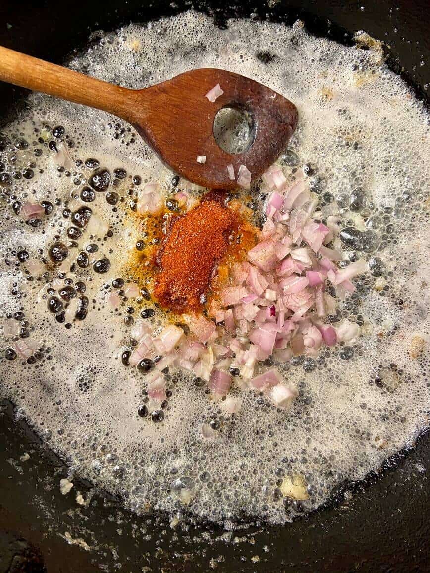 Sauteing shallots and spices in a pan.