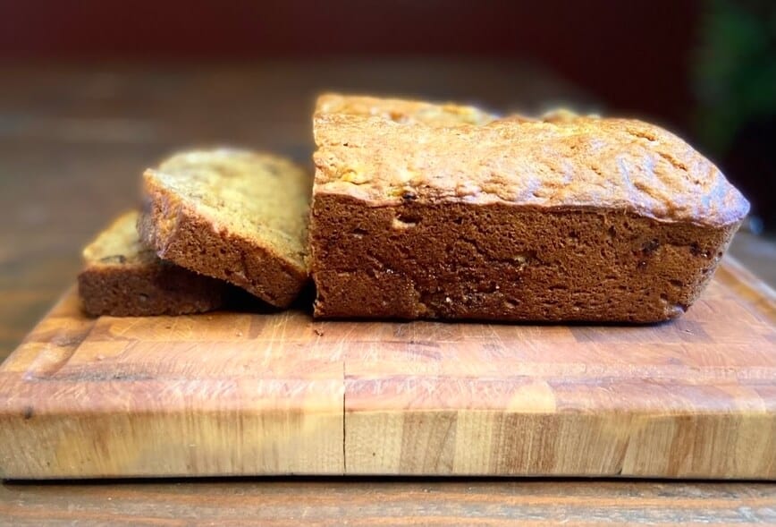 Baked and sliced bread on a wood cutting board.