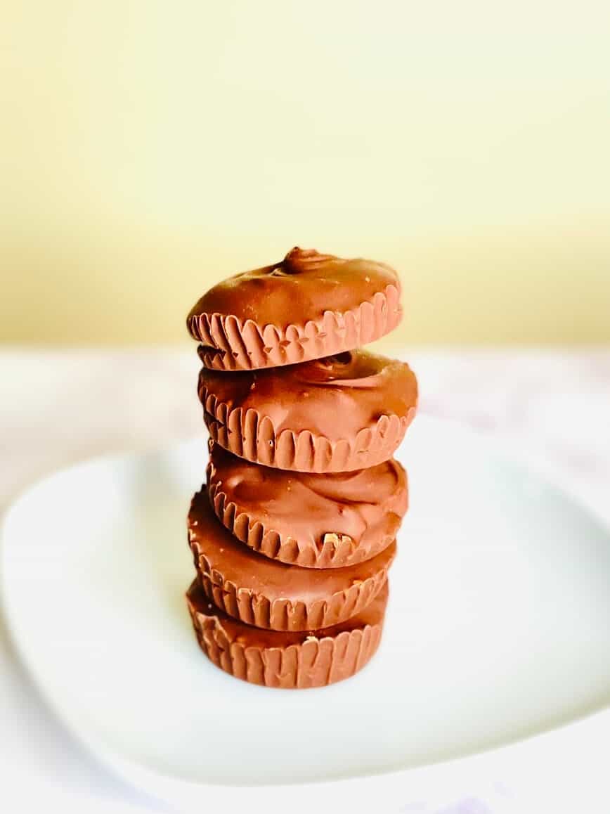 5 peanut butter cups stacked up on a white plate.