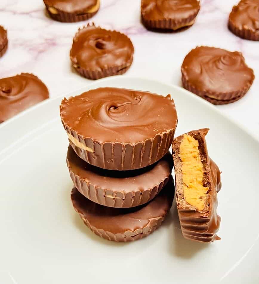 Peanut butter cups stacked on a plate, with one with a bite out of it.