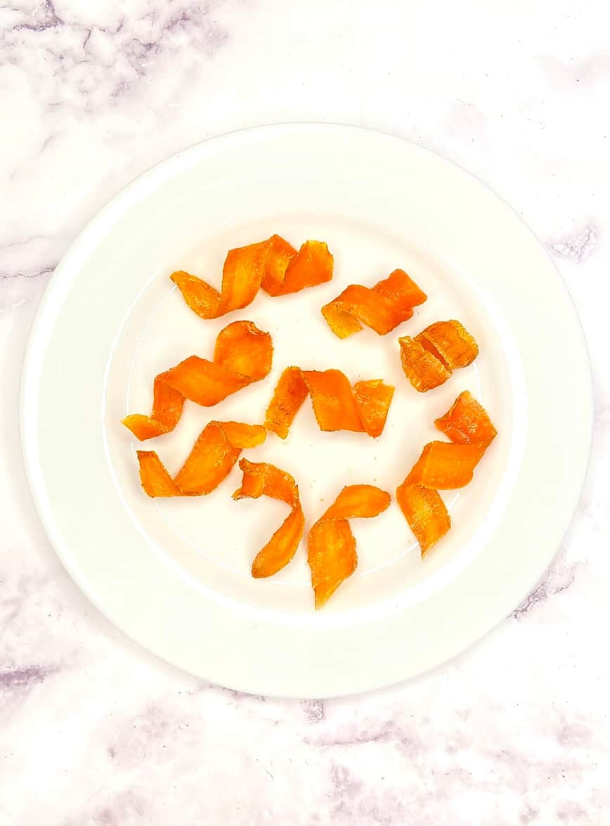 Curled carrot curls on a white plate.