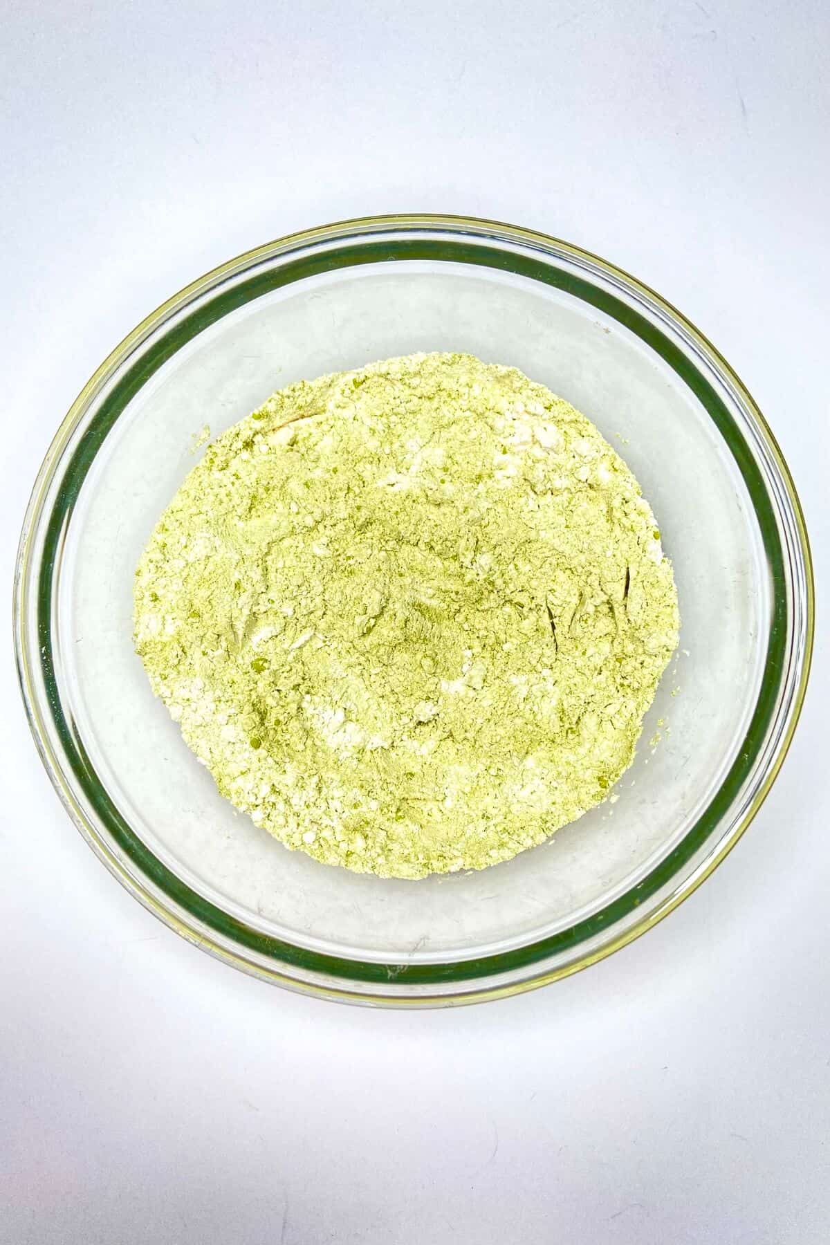 Flour, matcha powder, and baking powder mixed together in a glass bowl.