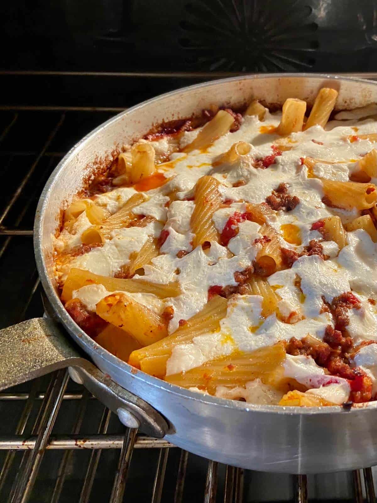 Baked pasta with sauce and cheese in pan.