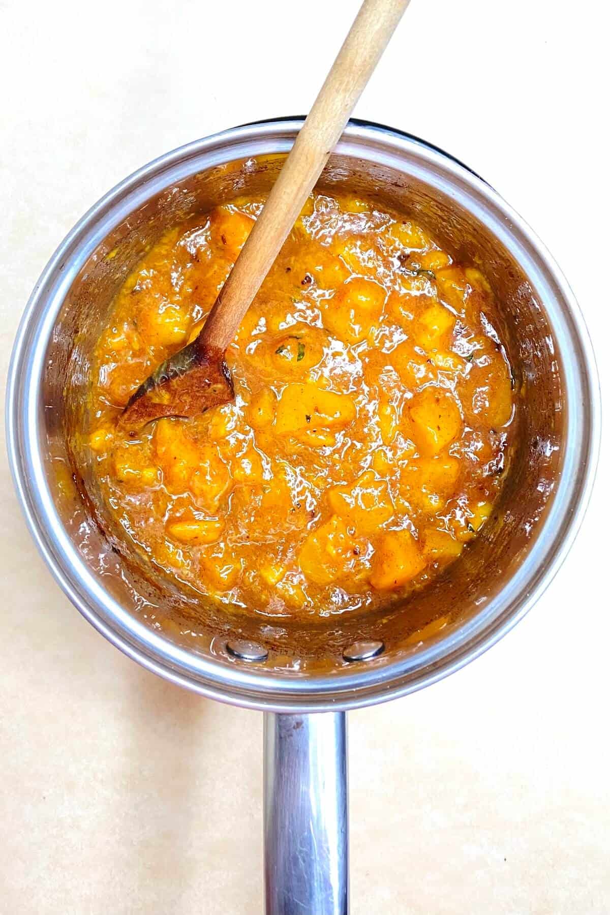 Cooking the peach and mango filling in a pot with a wooden spoon.