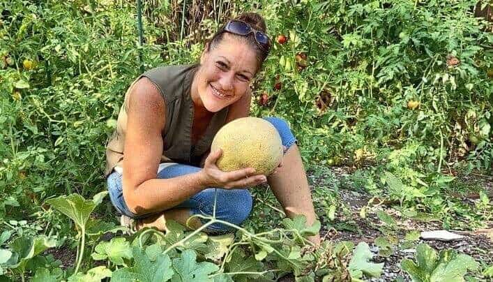 Viana picking a cantaloupe from our garden.