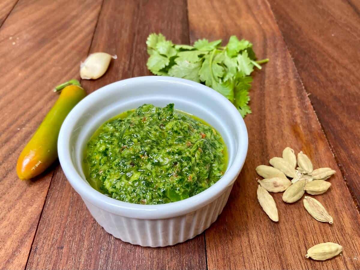 Sauce in a ramekin, with ingredients on wood table.