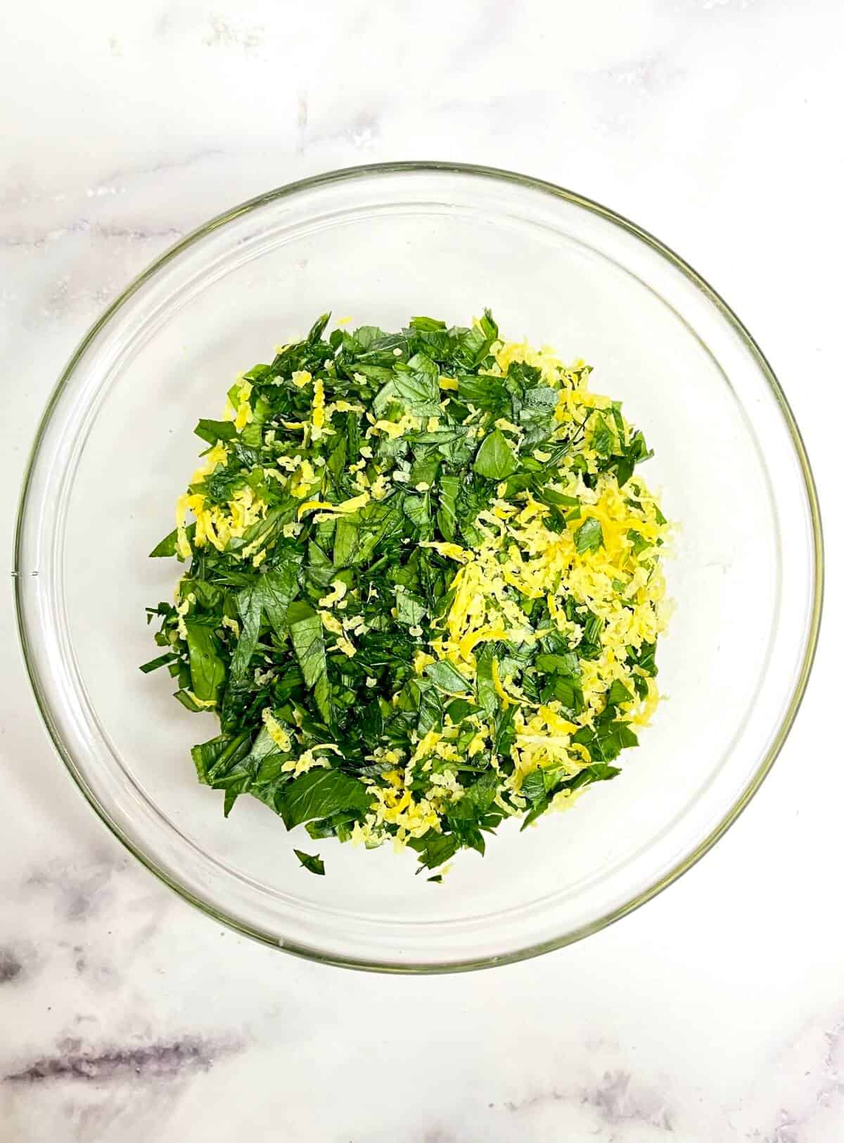 Chopped parsley and lemon zest in a glass bowl.
